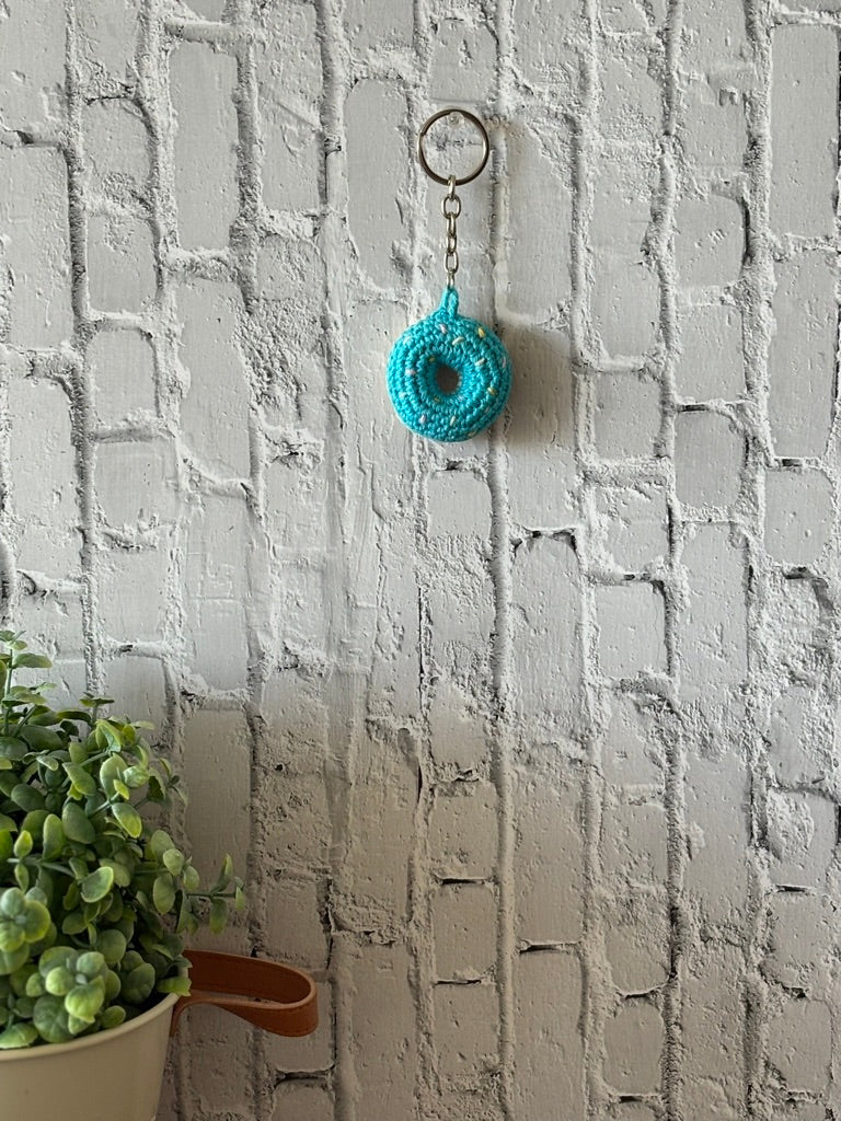 Blue crochet donut keychain hanging on wall, handmade in Toronto