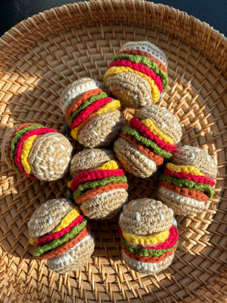 Nine crochet burger fridge magnets in a woven basket