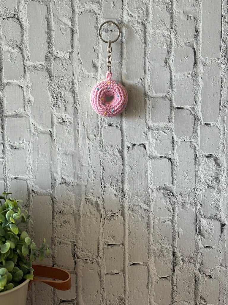 Pink crochet donut keychain hanging on wall, handmade in Toronto