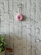 Pink crochet donut keychain hanging on wall, handmade in Toronto