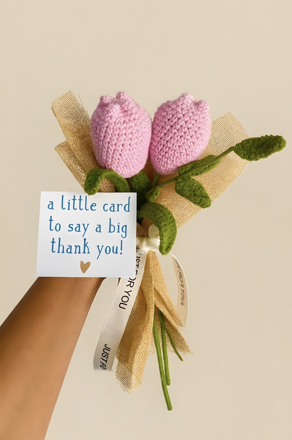 Two pink crochet tulips wrapped in jute with a thank-you card