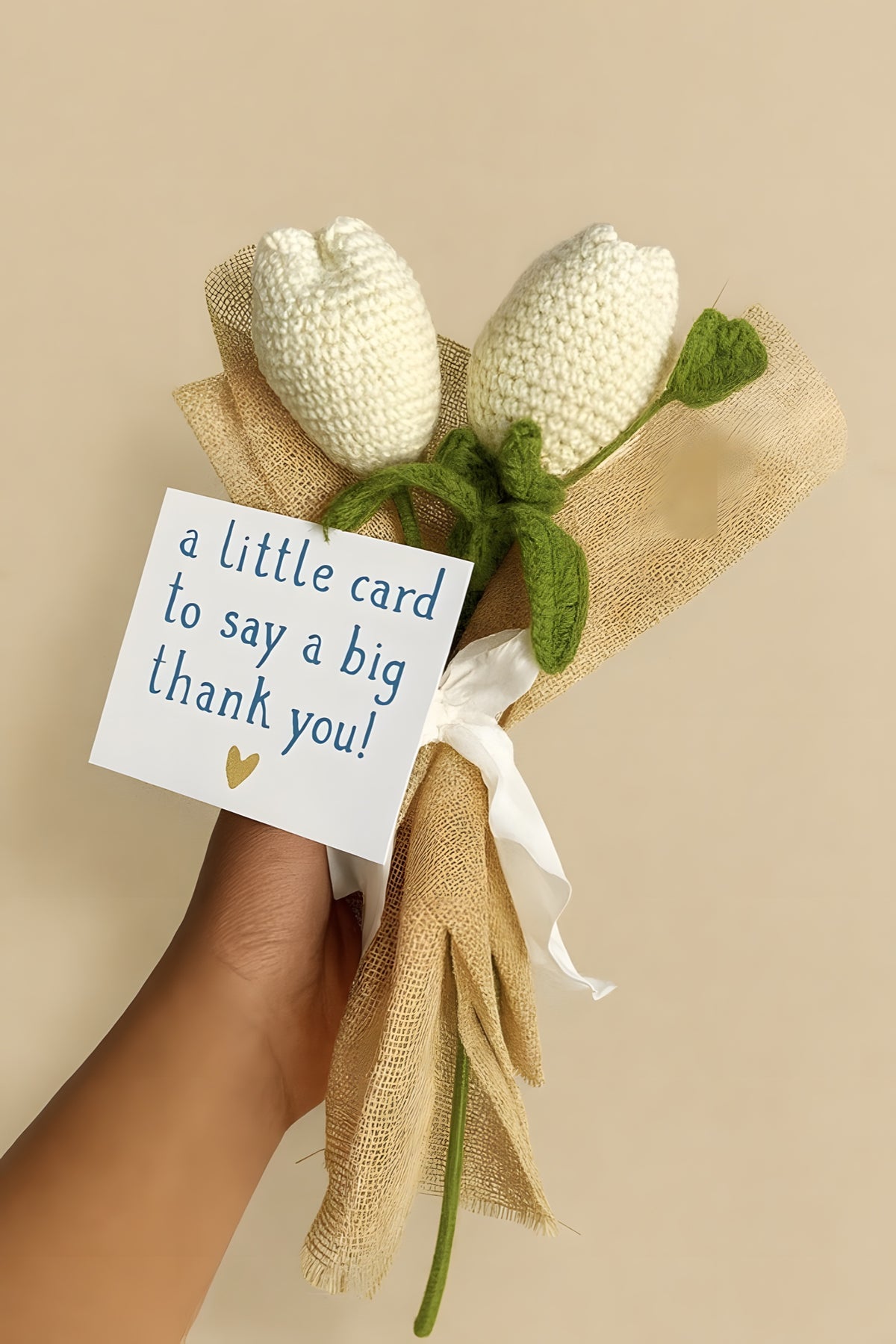 Two white crochet tulips wrapped in jute with a thank-you card