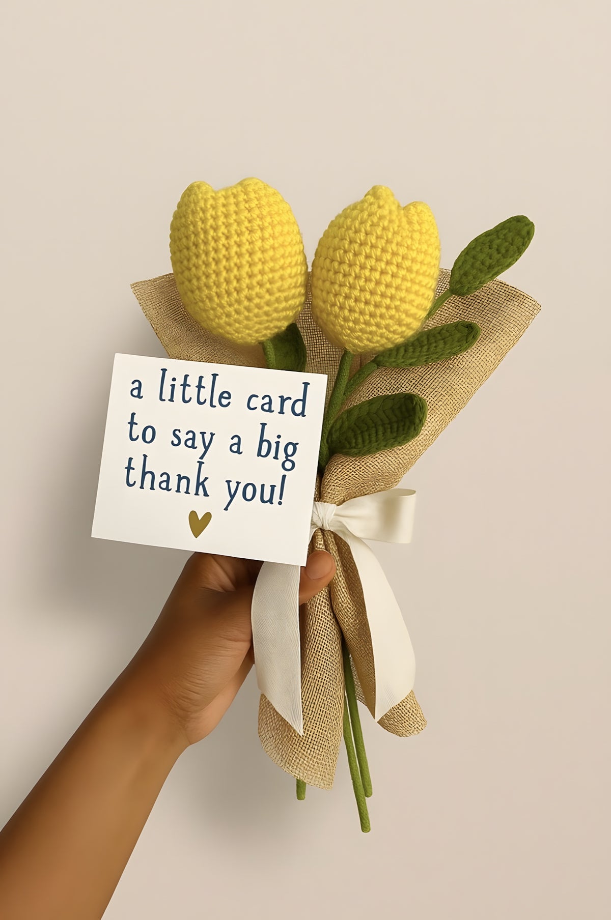 Two yellow crochet tulips wrapped in jute with a thank-you card