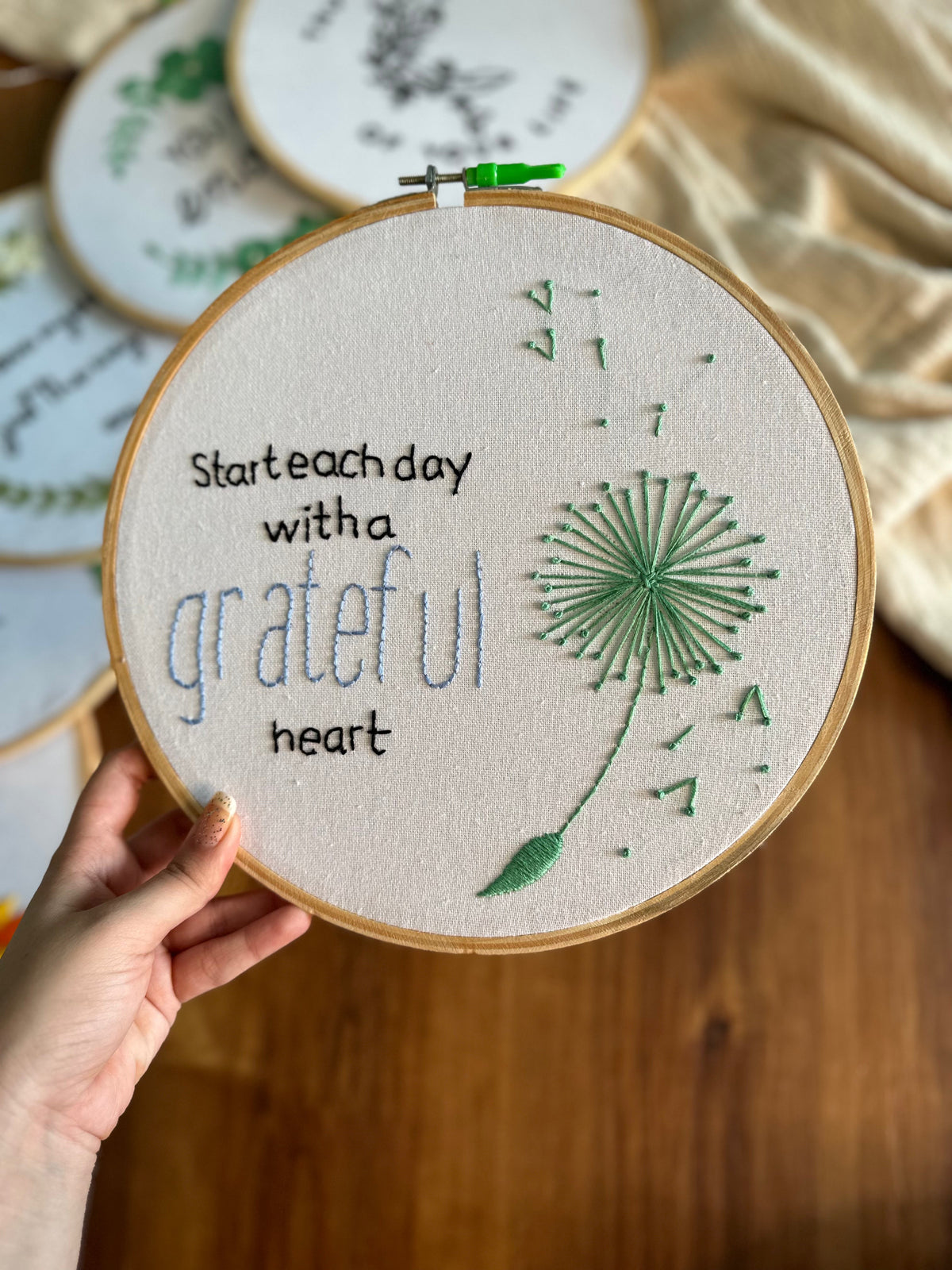 Embroidery hoop reading Start each day with a grateful heart, with a green dandelion